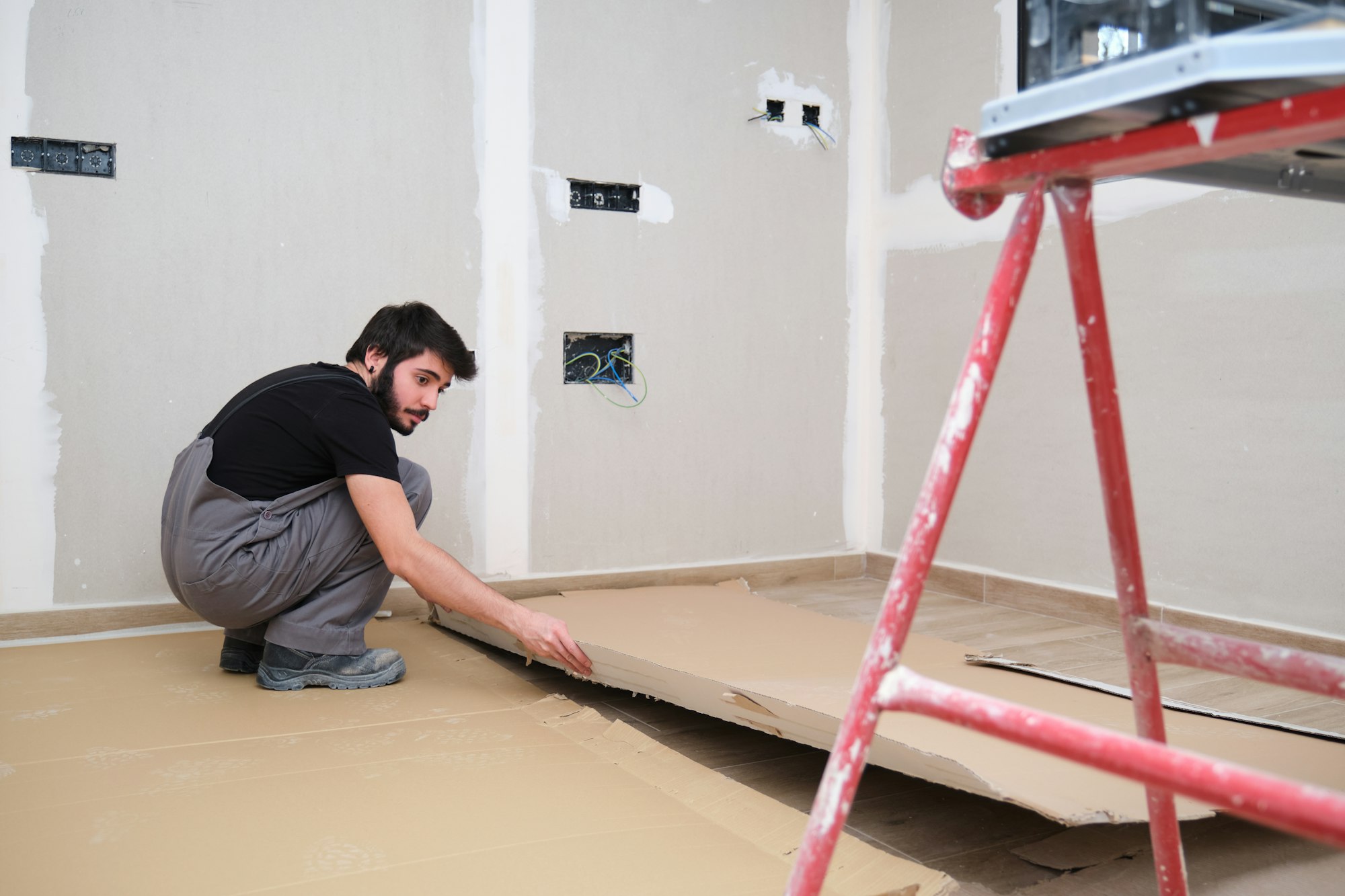Painter using cardboard to cover the wood floor before painting the room.