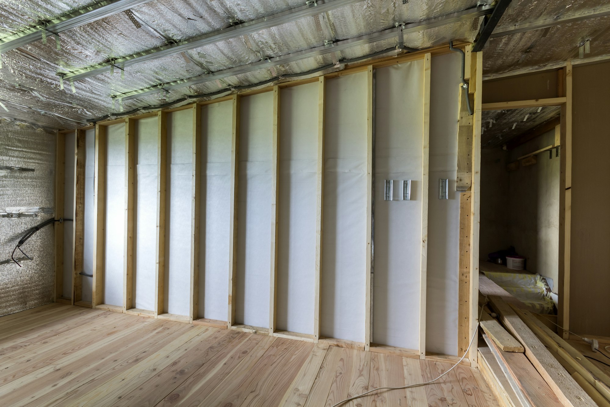 Room under construction and renovation with silver aluminum foil on walls and ceiling, oak floor and